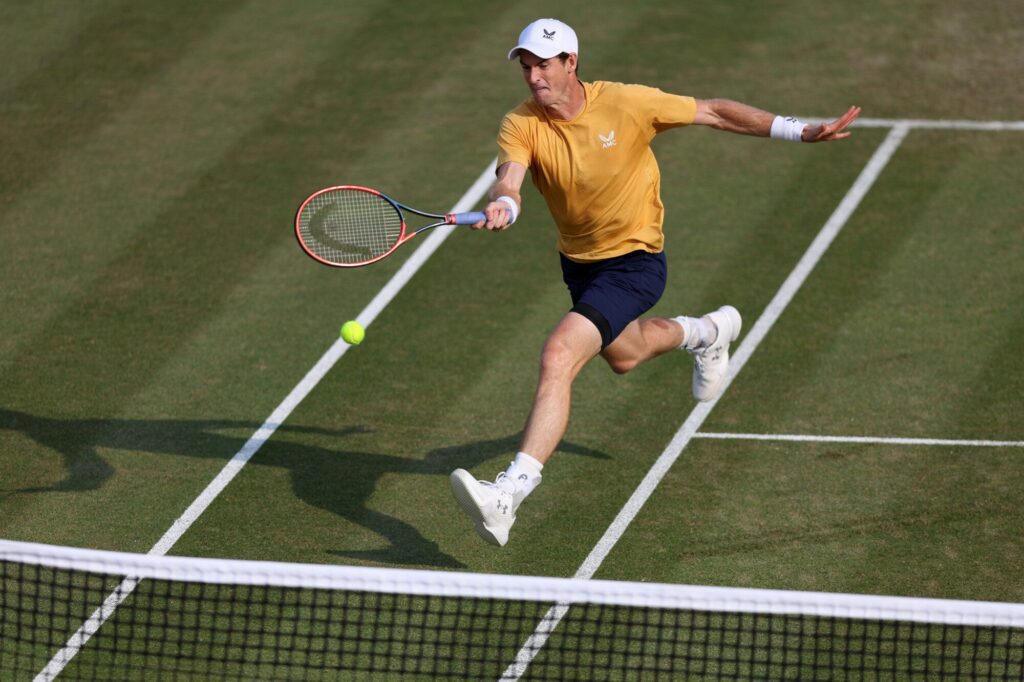 Andy Murray executing a powerful tennis shot on grass court.