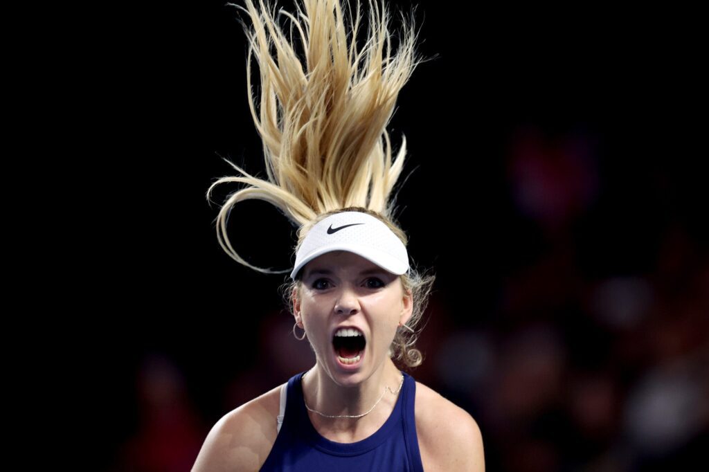 A female tennis player celebrating a victory with her hair dramatically lifted.