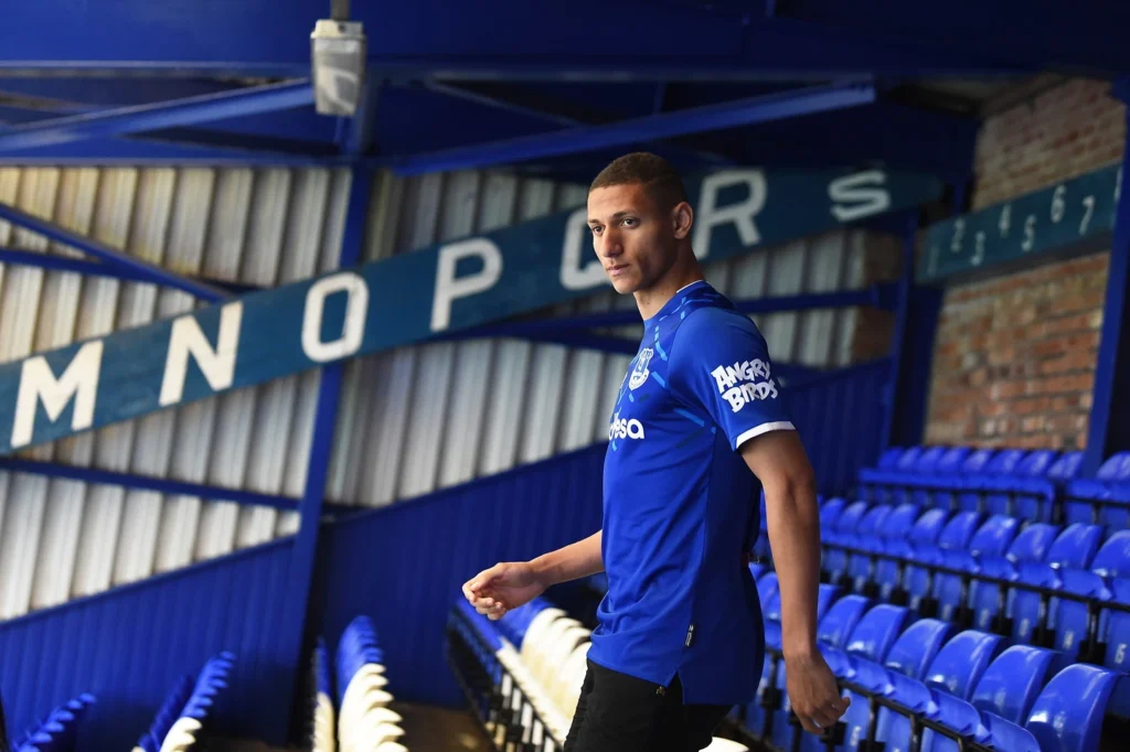 Richarlison walking through Everton stadium seating area.