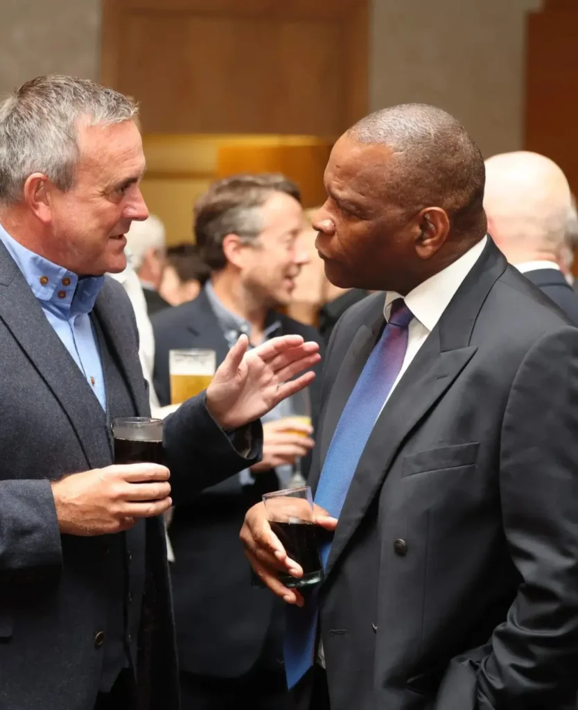 Two men engaging in conversation at a business networking event, holding drinks.