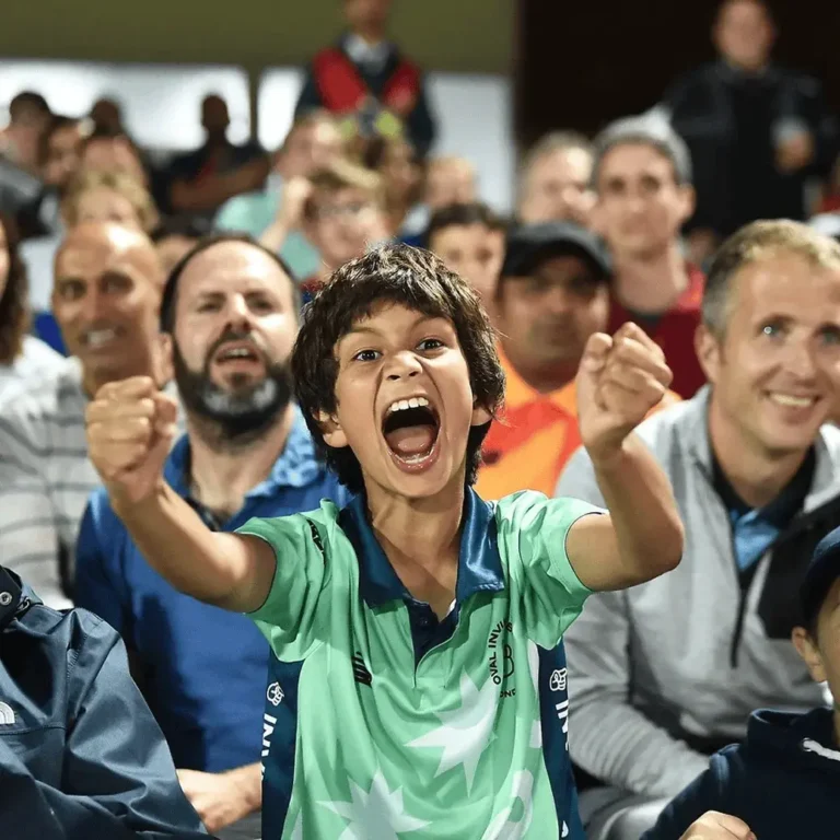 A young boy joyfully celebrating in a crowd at a sports event.