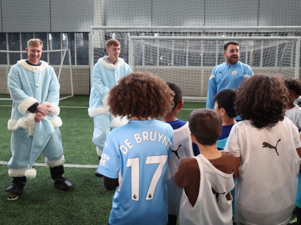 A fun football training session with children and players in blue costumes.