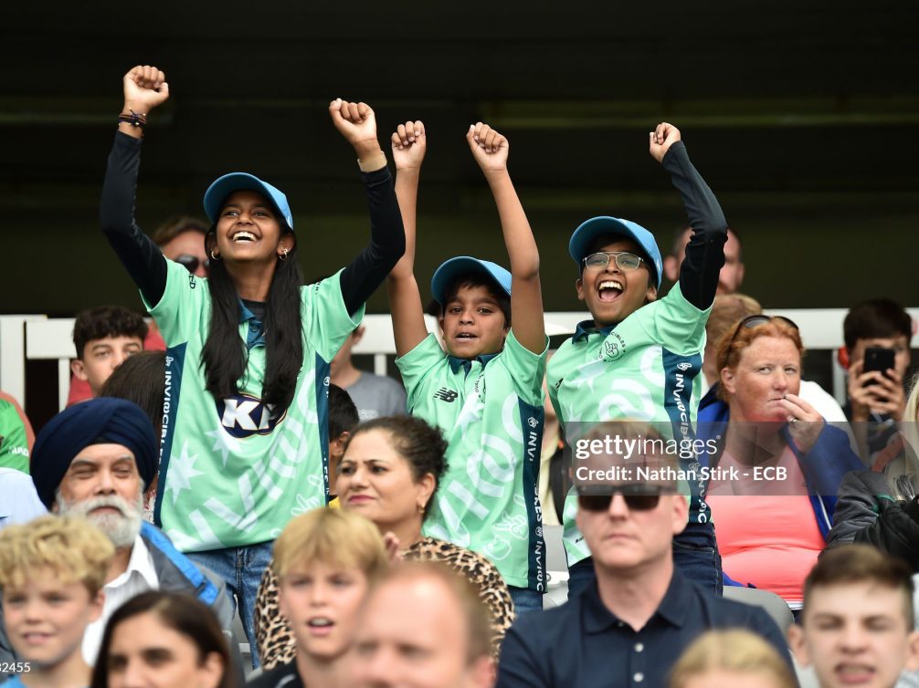 Kids in team jerseys cheering joyfully at a cricket match.