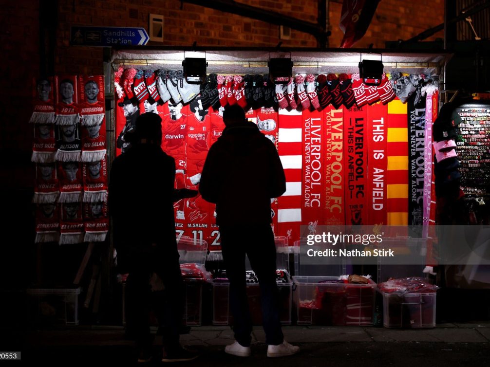 A vibrant Liverpool FC merchandise stall featuring scarves and clothing.