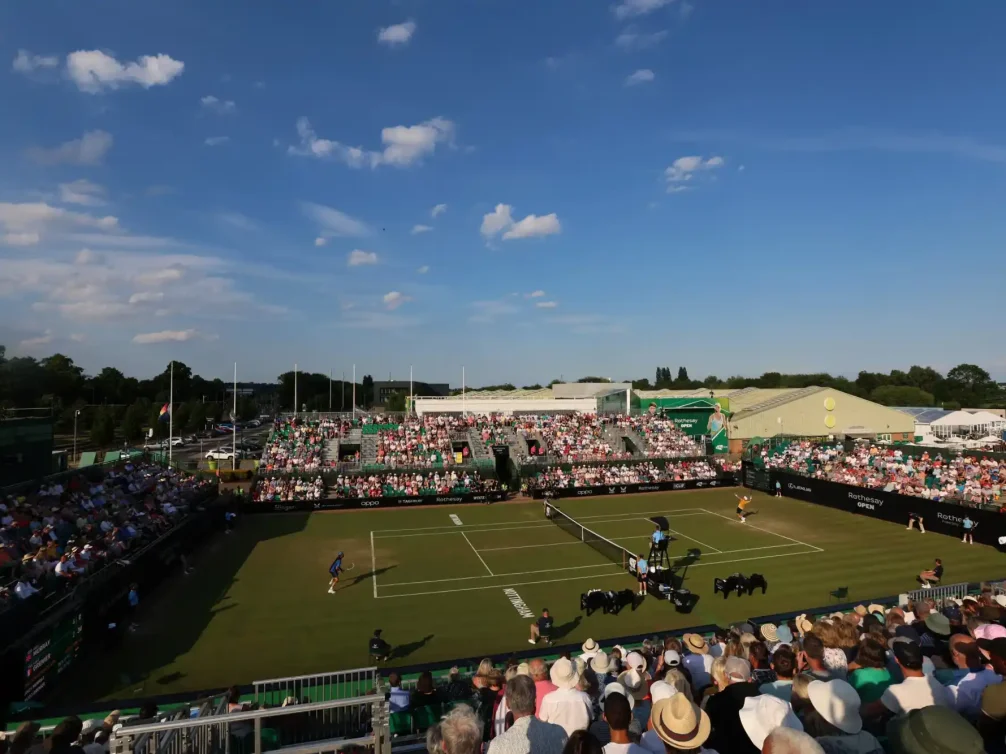 A panoramic view of the crowd watching a tennis match at the Rothesay Open, showcasing an enthusiastic audience.
