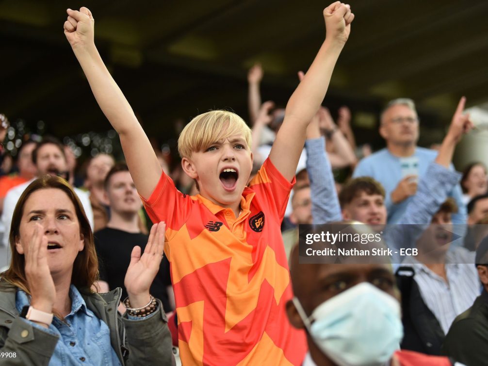 A close-up of a boy celebrating in a crowd at a sports event, expressing joy and excitement.